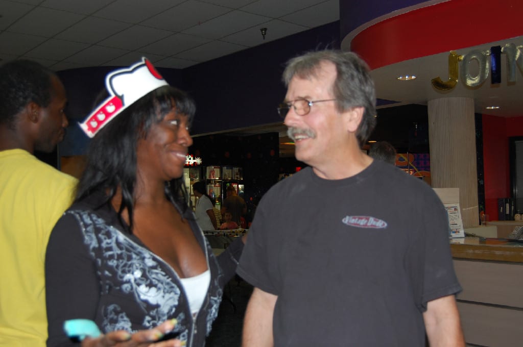 A Man Standing and Chatting with a Woman with Paper Hat