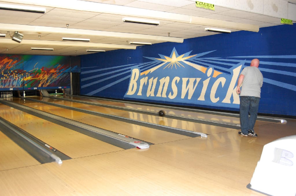 A Bald Man in Action Near the Sidewall of the Bowling Alley