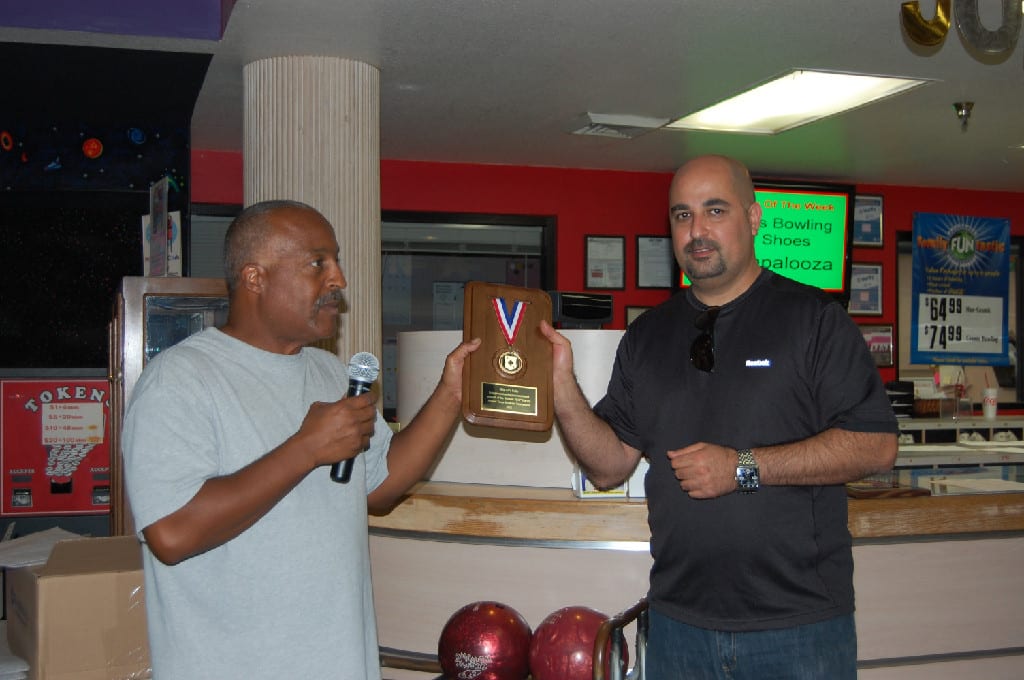 Two Persons Holding A Wooden Plaque at the Bowling Alley