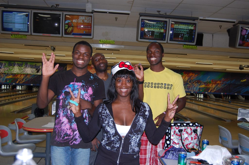 A Bowling Team Smiling and Posing with Victory Sign