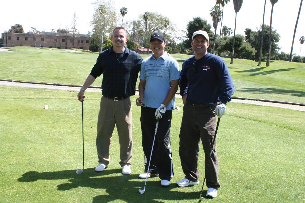Three Men with Golf Clubs and Gloves Standing on the Golf Course