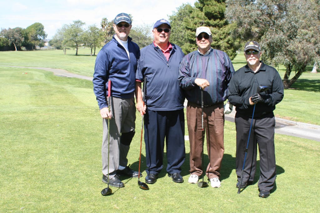 Four Golf Players Standing with Golf Clubs with Dense Vegetation in the Back