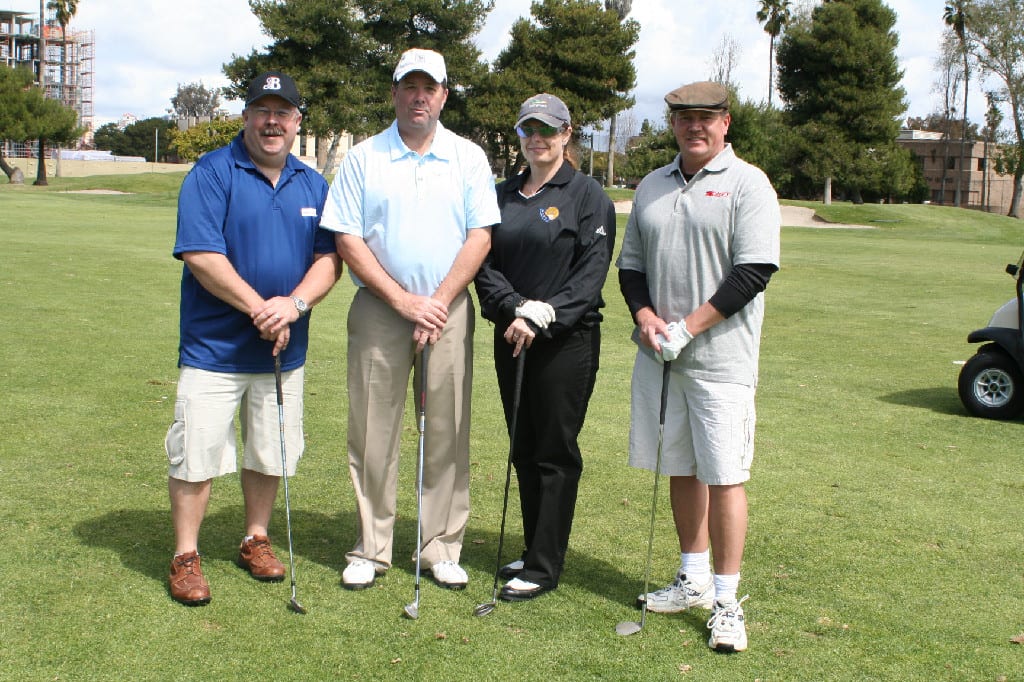 Three Men and One Female Golfer with Clubs Standing for Photo