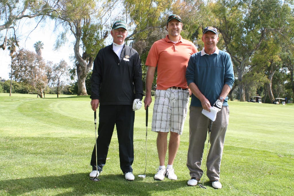 Three Golfers with Club with Dense Vegetation Behind