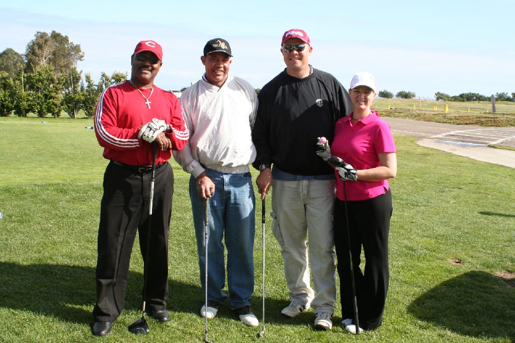 Three Male and One Female Golfers with Clubs on the Golf Course