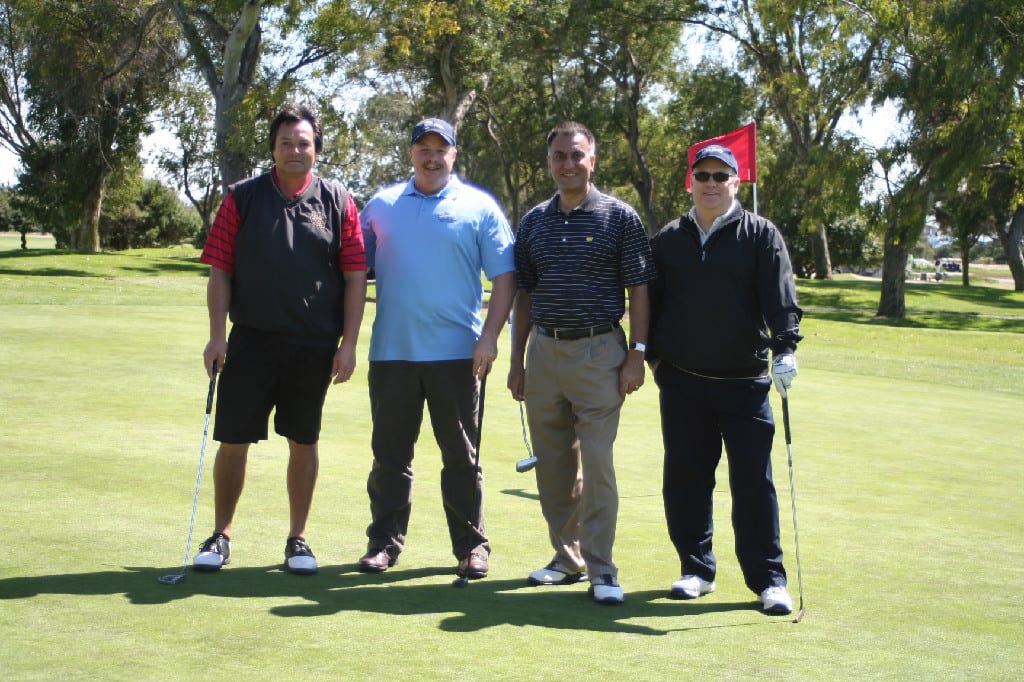 Four Middle Aged Golfers with Clubs Standing for Photo