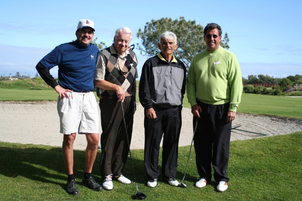 Four Seasoned Golf Players with Golf Clubs Standing on Golf Course